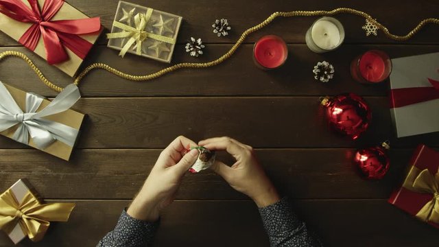 Man opens candy, eats it and throws wrapper on Christmas decorated desk, top down shot
