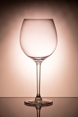 One empty wineglass for red wine on diffusion lit background 
