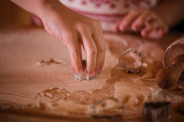 young girl making christmas cookies in the kitchen cutting out shapes 