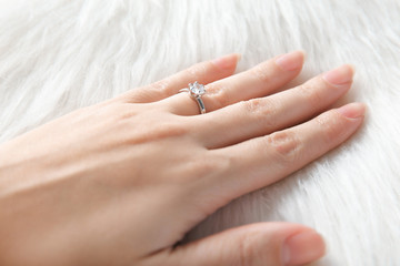 Woman's hand with luxury engagement ring on fur, closeup