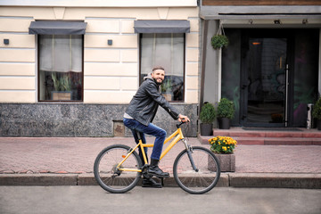 Attractive young hipster riding bicycle on city street