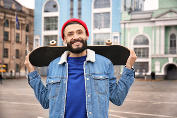 Attractive young hipster with skateboard on city street © Africa Studio