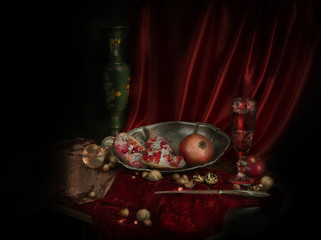 On the table covered with red velvet cloth is tin dish of juicy grenades. Next to a glass of wine.