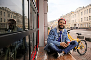Attractive young hipster with smartphone on city street
