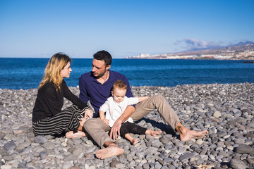 Mom and dad at the beach play and pamper their baby