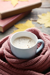 Cup of coffee with pink scarf on wooden table