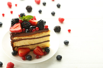 Piece of chocolate cake with berries in plate on wooden table