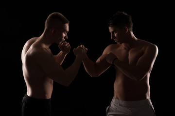 Fototapeta na wymiar Two fighters facing each other on black background