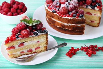 Homemade biscuit cake with berries on mint wooden table