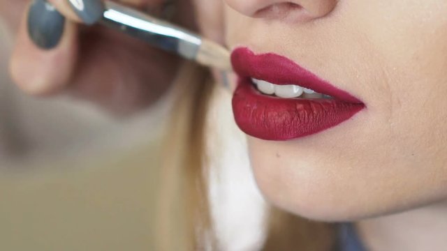 Macro shoot of applying pomade on lips by artist's hands. Slowly