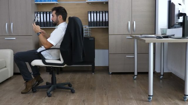 Young business person in the office sliding on the chair while taking notes in papper notebook. Long work hours