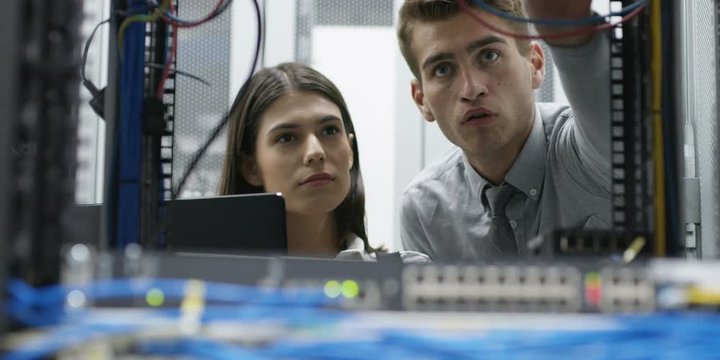 Team of people working in a data centre with rows of server racks and super computers. Shot on RED Helium 8K