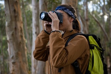 Hiker woman clicking a photo in forest