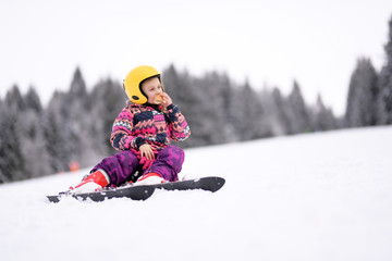 Fototapeta na wymiar Happy little girl skiing downhill