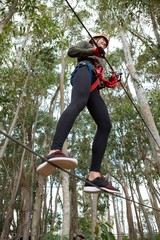 Young smiling woman wearing safety helmet crossing zip line 