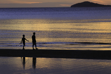 Fototapeta na wymiar the silhouette photo of two brothers enjoy on the beach with colorful sea in sunrise