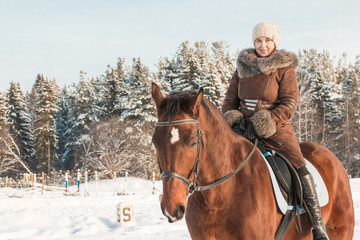 Woman in brown dress and brown horse in a winter