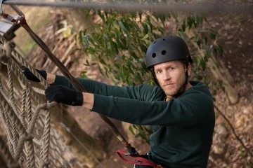 Fototapeta premium Male hiker wearing helmet climbing rope fence