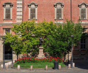 Fototapeta na wymiar square of Milan, Italy,..with a small flowerbed at the entrance of an ancient palace