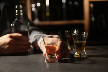 Woman with bottle and glass of brandy in bar. Alcohol dependence concept