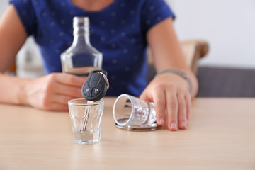 Car key in glass shot and blurred drunk woman on background. Don't drink and drive concept