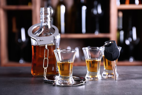 Glassware of alcohol with handcuffs and car key on table in bar. Don't drink and drive concept