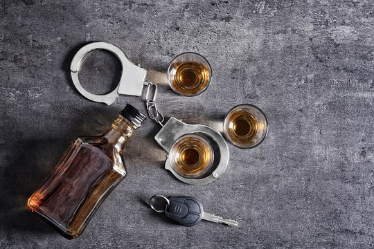 Composition with alcohol, handcuffs and car key on grey background. Don't drink and drive concept