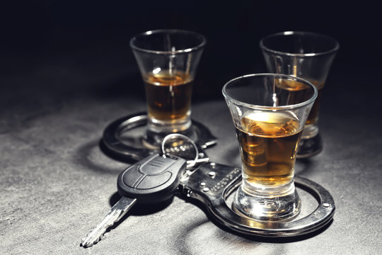 Composition with alcohol, handcuffs and car key on table. Don't drink and drive concept