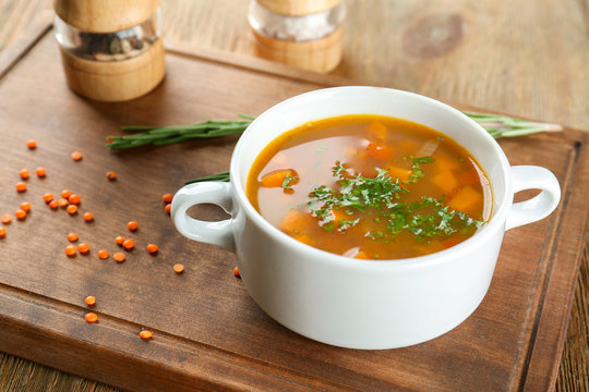Dish with tasty lentil soup on wooden board