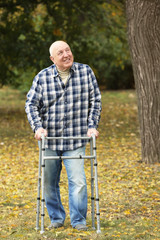 Elderly man with walking frame in autumn park
