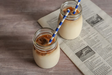 Glass jars with delicious iced coffee on table