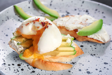 Tasty bruschetta with egg and avocado on plate, closeup