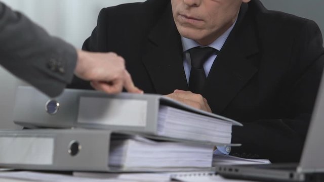Pile of folders in front of upset manager, female boss giving orders to man