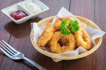 Fried calamari rings in wicker basket and sauce.