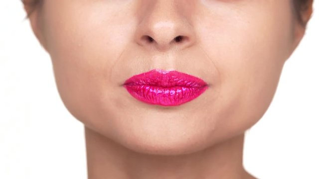 Extreme closeup portrait of serious woman wearing dazzling pink lipstick expressing shock with opening her mouth over white background. Concept of emotions