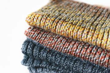 Pile of knitted winter scarfs on straw basket isolated on white background. Free copy space.