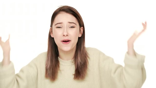 Studio portrait of annoyed long-haired woman in sweater gesturing in stress screaming asking why being angry over white background closeup. Concept of emotions