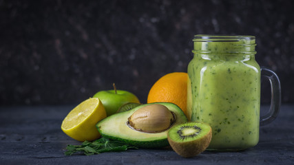 Smoothies from avocados, bananas, kiwi and herbs on a black wooden dark table. Diet vegetarian food.