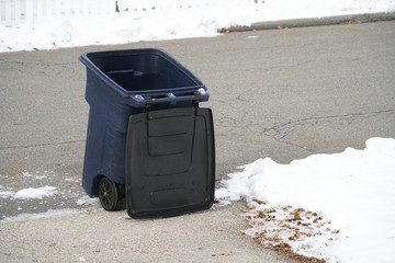 Trash bin at the side of street in winter with lip open