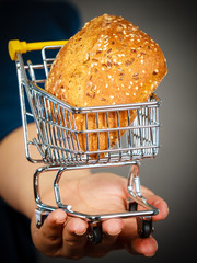 Woman hand holding shopping cart with bread