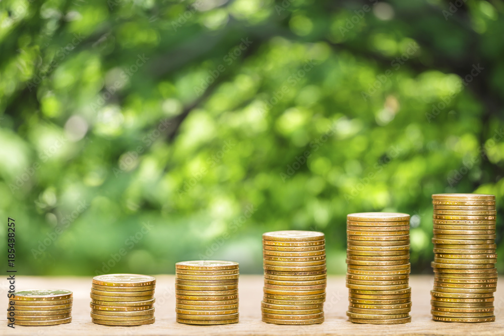 Wall mural money coins arranged as a graph on wooden table with natural bokeh background, concept of business g