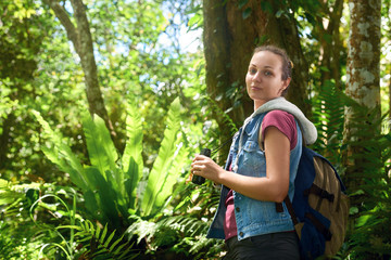 Portrait of female tourist with binoculars in hand in the tropical rain forest.