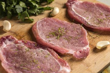 Close up of pork chops on a cutting board with herbs