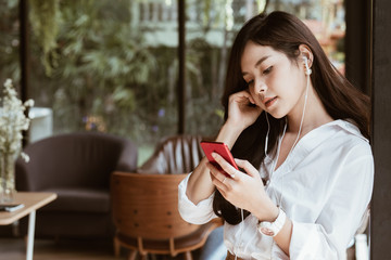 woman holding smartphone and listening to music with headphones at cafe. leisure, lifestyle, people concept