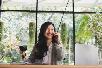 Fototapeta premium businesswoman talk on smart phone at workplace. startup woman working with business plan report document at office. young female entrepreneur hold coffee cup at cafe. 
