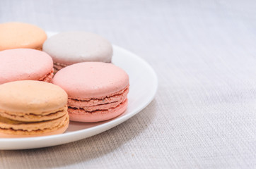 Delicious cake macaroons on plate on light background, close up