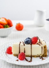 Delicious cheesecake with strawberry on a table against white wall.