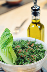 Vegetarian salad Tabbouleh close up in a bowl and bottle for olive oil.