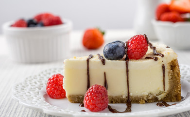 Delicious cheesecake with strawberry on a table against white wall.
