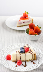Delicious cheesecake with strawberry on a table against white wall.